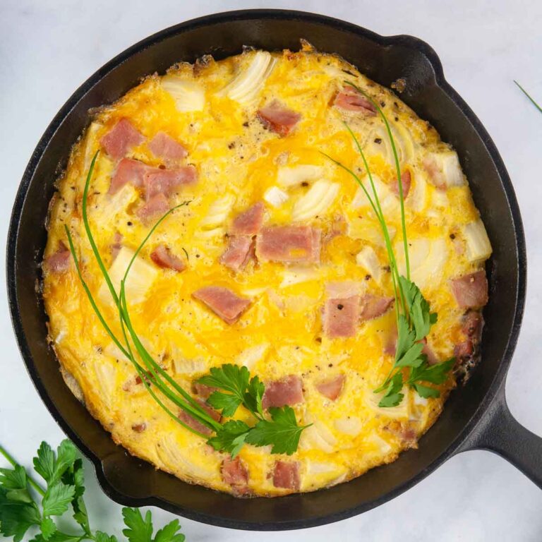 Ham and Cheese Frittata is a kind of crustless quiche shown in a cast iron skillet that makes a lovely breakfast or brunch