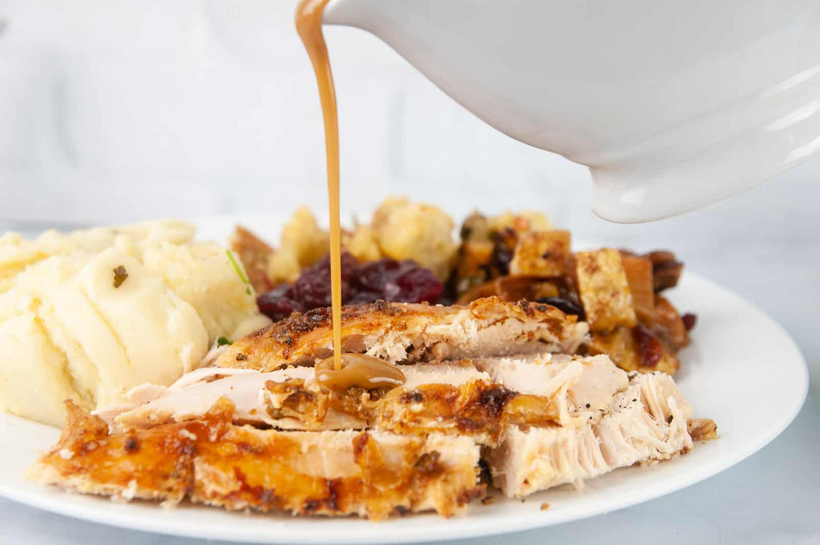 Gravy being poured onto a turkey dinner plate