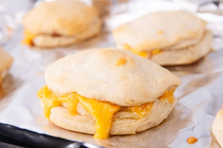 Bake the ham and cheese biscuit sandwiches until the tops are golden brown and the cheese melts.