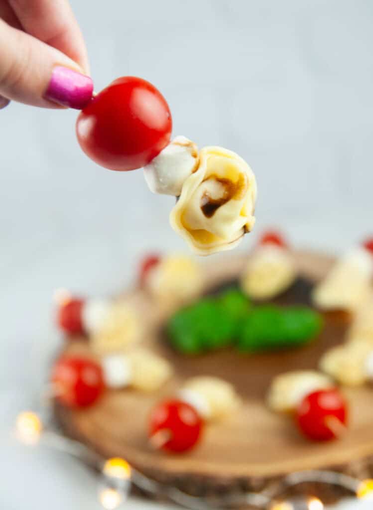 A Tortellini Caprese Skewer being picked up off a serving platter