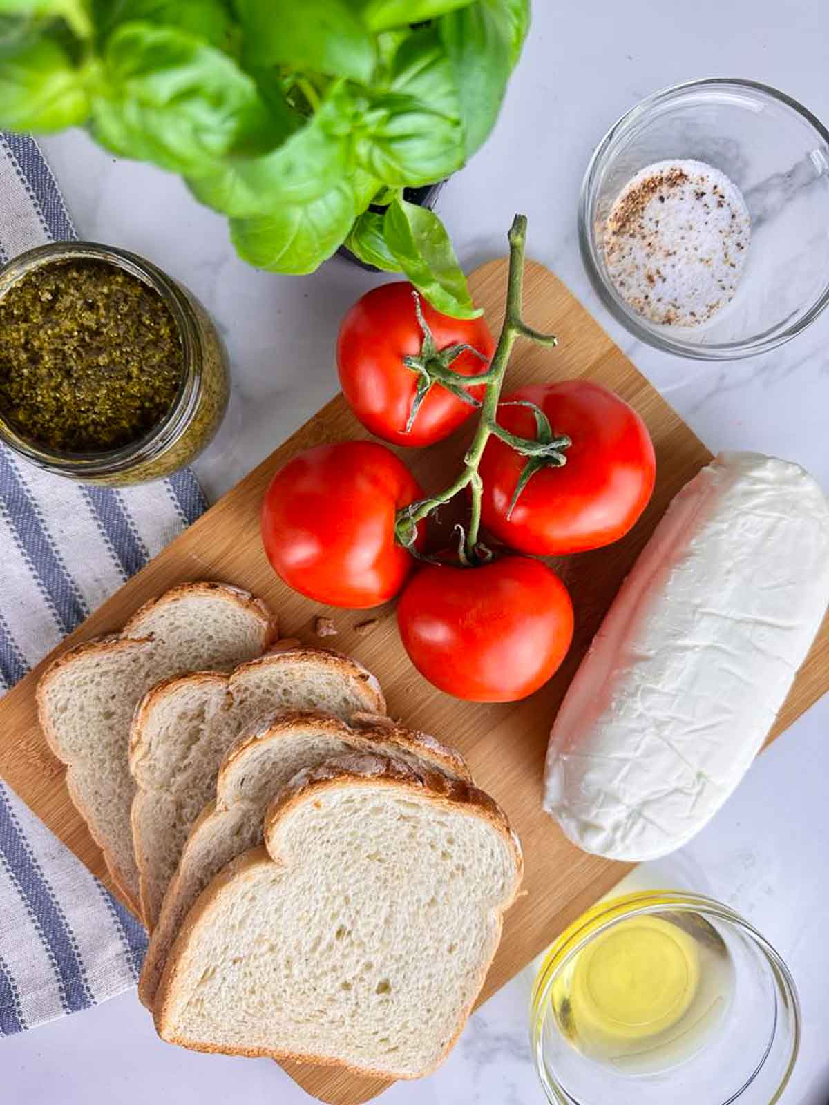 Ingredients for Caprese Panini Sandwich with Pesto: Bread, Tomatoes, Basil, Mozzarella, Pesto, Olive Oil, Salt and Pepper