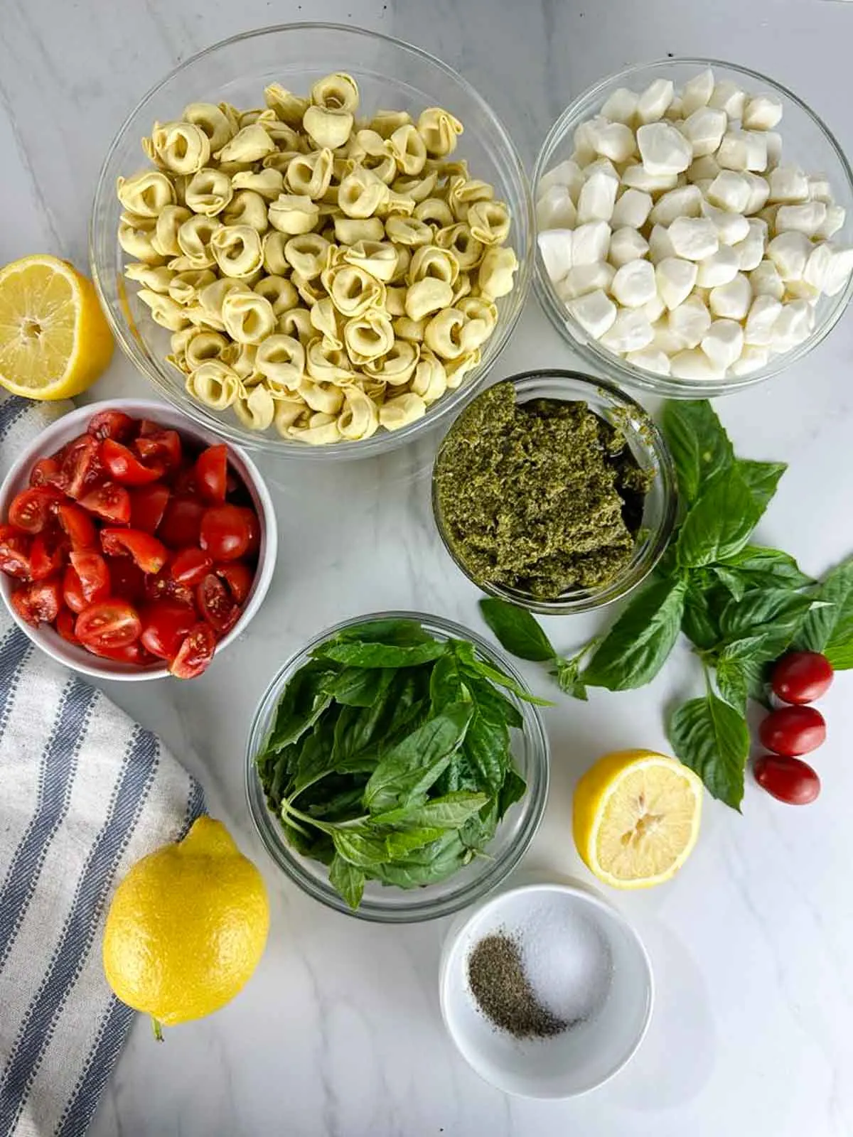 Ingredients for Caprese Tortellini Pasta Salad with Pest: Tortellini, Mozzarella, Tomatoes, Basil, Pesto, Lemon Juice, Salt and Pepper