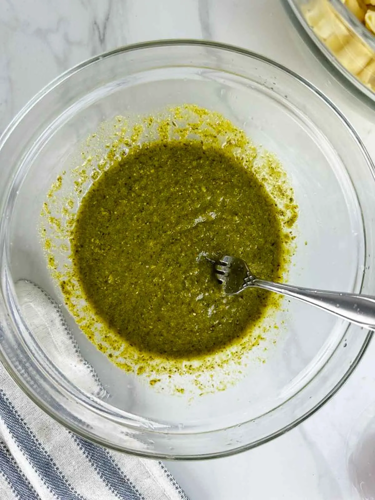 Pesto and lemon juice in a bowl stirred together to a thinner consistency than regular pesto.