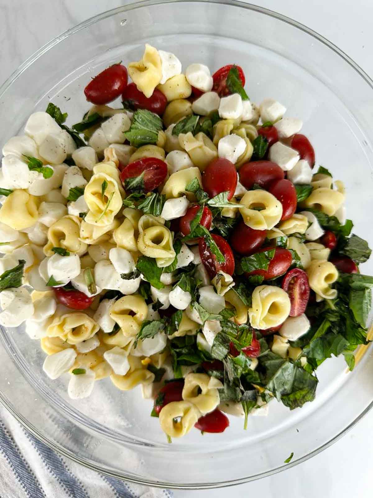 Toss the ingredients for Caprese Tortellini Pasta Salad together in a bowl.
