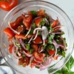 Toss the tomato and onion salad with vinegar dressing until everything is evenly coated.