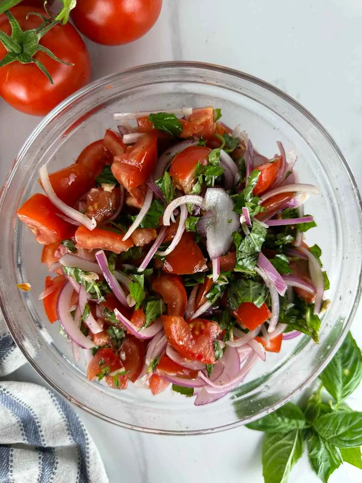 Toss the tomato and onion salad with vinegar dressing until everything is evenly coated.