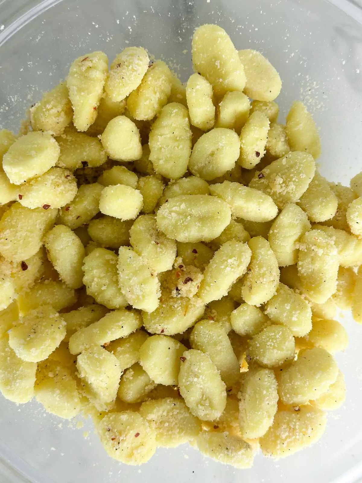 Toss the gnocchi with olive oil, Parmesan cheese, and seasonings to coat it.