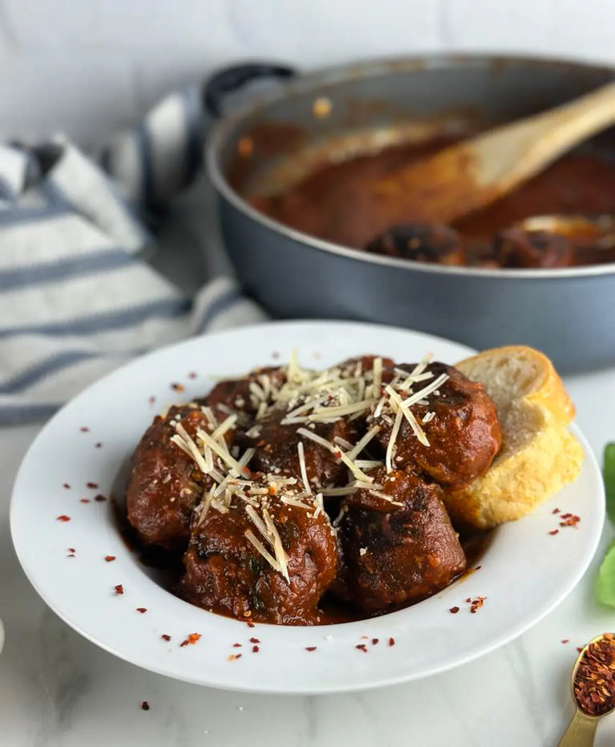 A bowl of Italian spicy meatballs in tomato sauce with parmesan cheese and bread