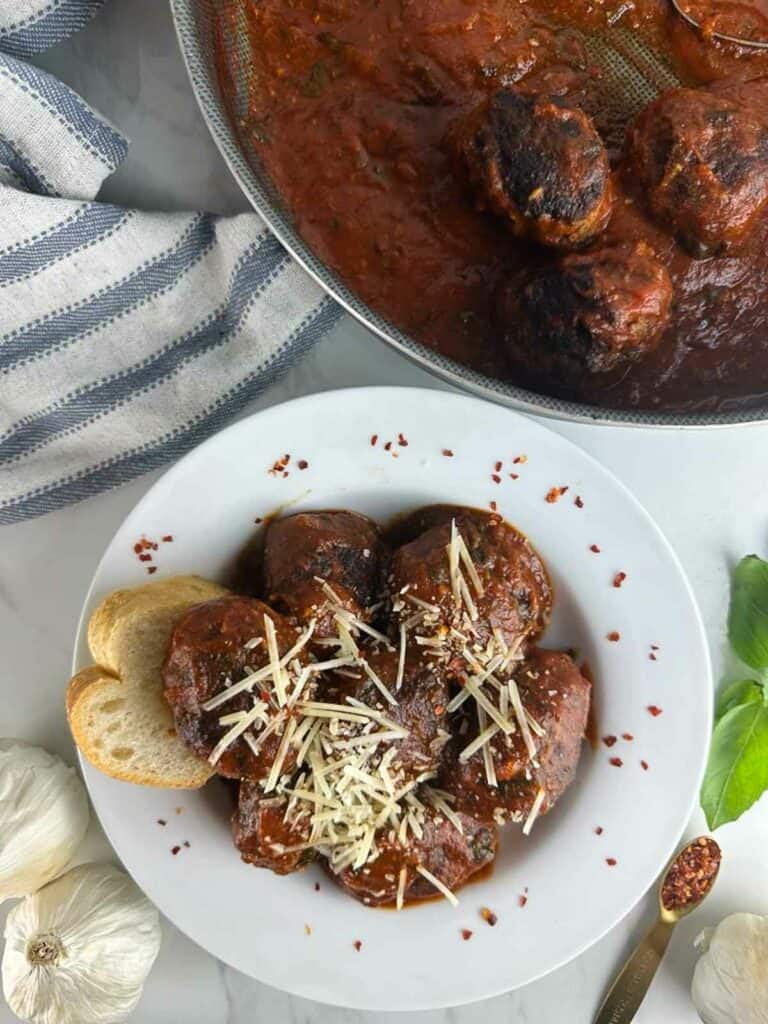 A bowl of Italian spicy meatballs in tomato sauce with parmesan cheese and bread