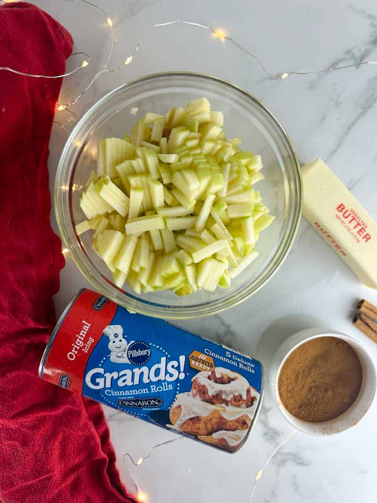 Ingredients for apple pie cinnamon rolls: cinnamon rolls, apples, butter, and cinnamon