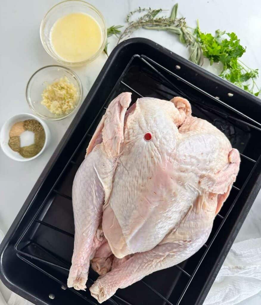 Ingredients for a turkey in a convection oven: whole turkey, melted butter, crushed garlic, seasonings, and fresh herbs.