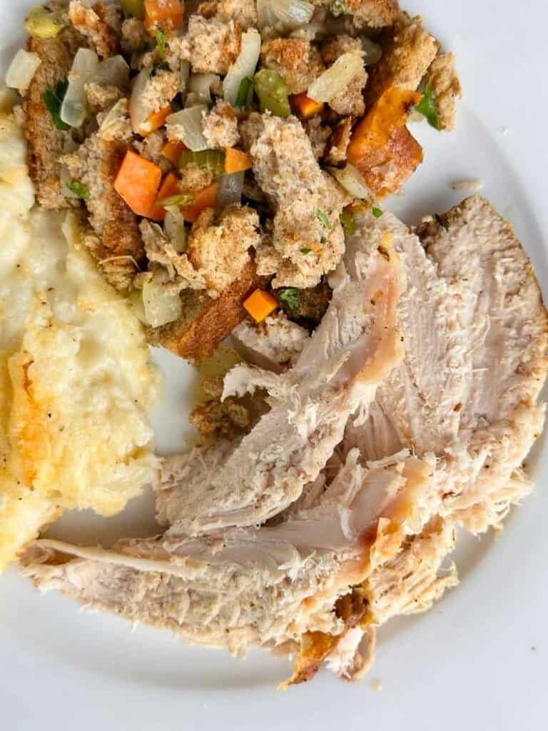 Serving of roasted turkey in a convection oven with stuffing and mashed potatoes.