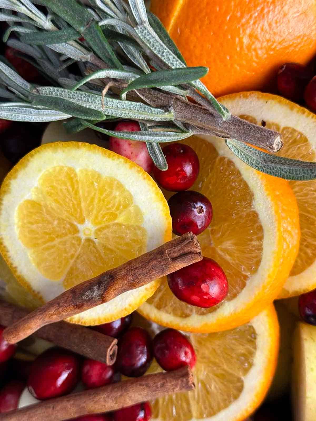 Add the oranges, apples, spices, and herbs to a large pot