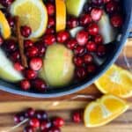 A Christmas simmer pot with extra oranges and cranberries around it