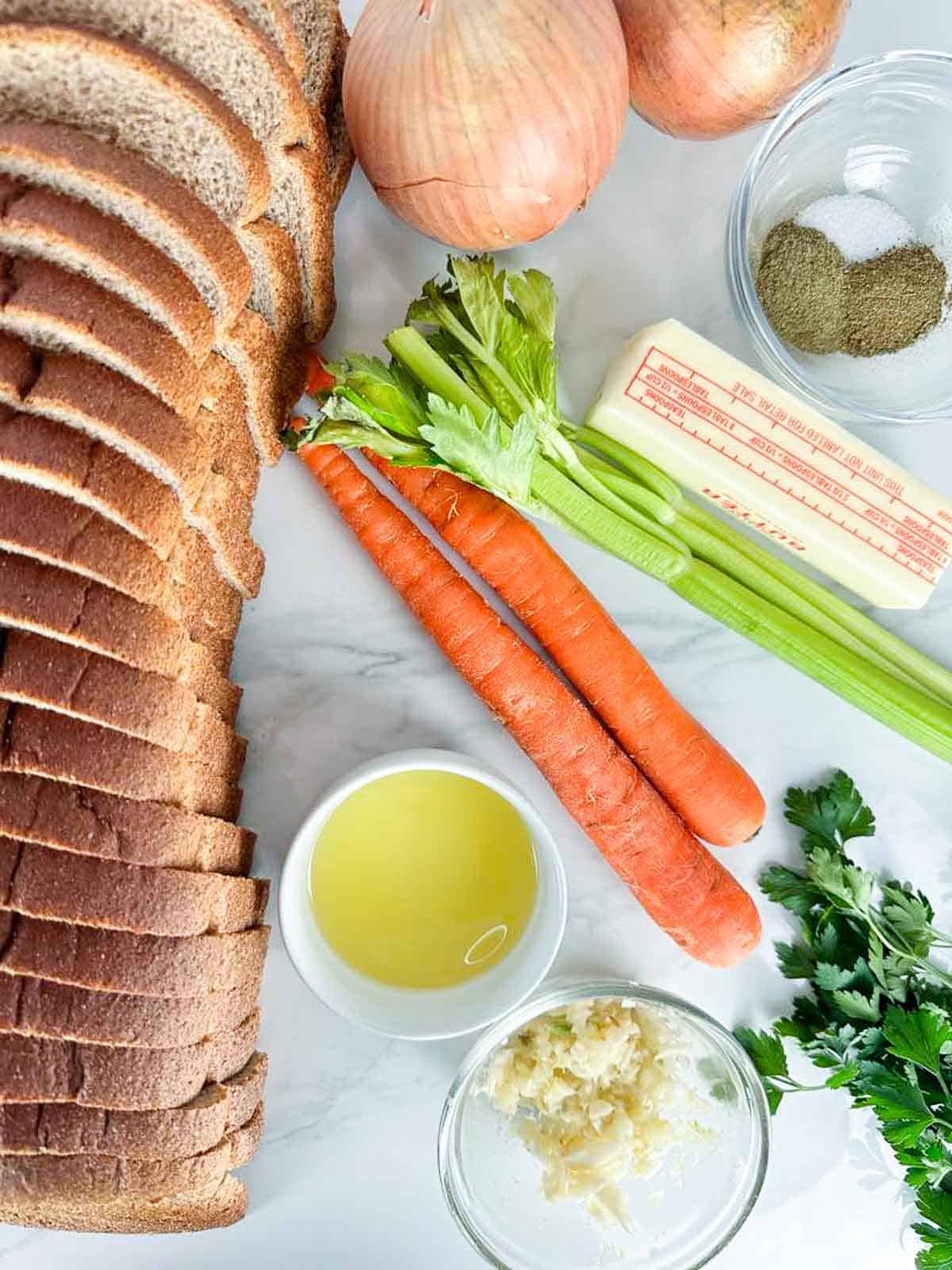 Ingredients for classic homemade stuffing: bread, garlic, oil, butter, celery, onions, dried herbs, and parsley