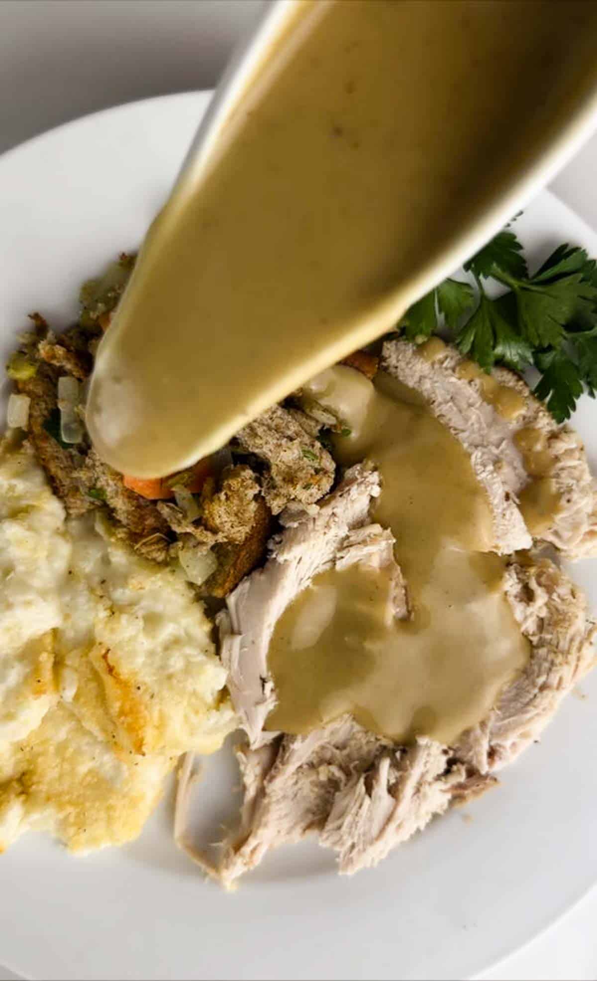 Turkey gravy from drippings poured over a plate of Thanksgiving dinner