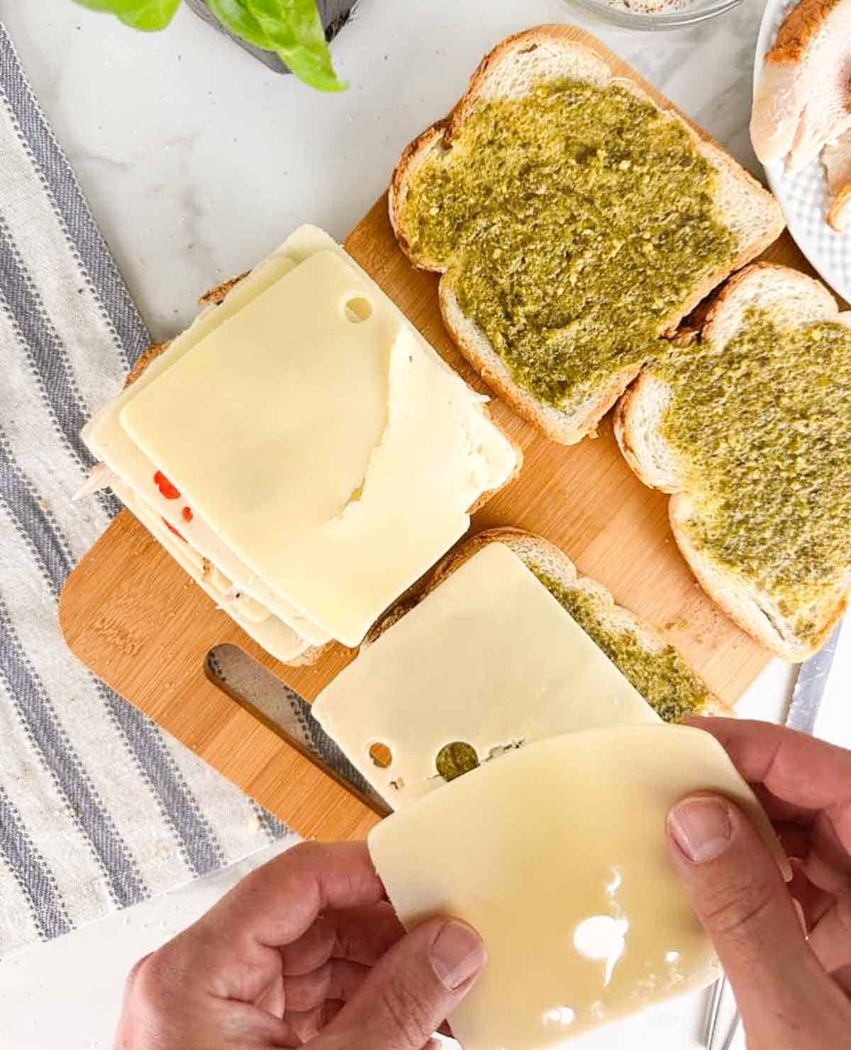 Build the turkey pesto panini by layering sliced cheese on to the pesto covered bread followed by turkey, tomato slices, and another slice of cheese.