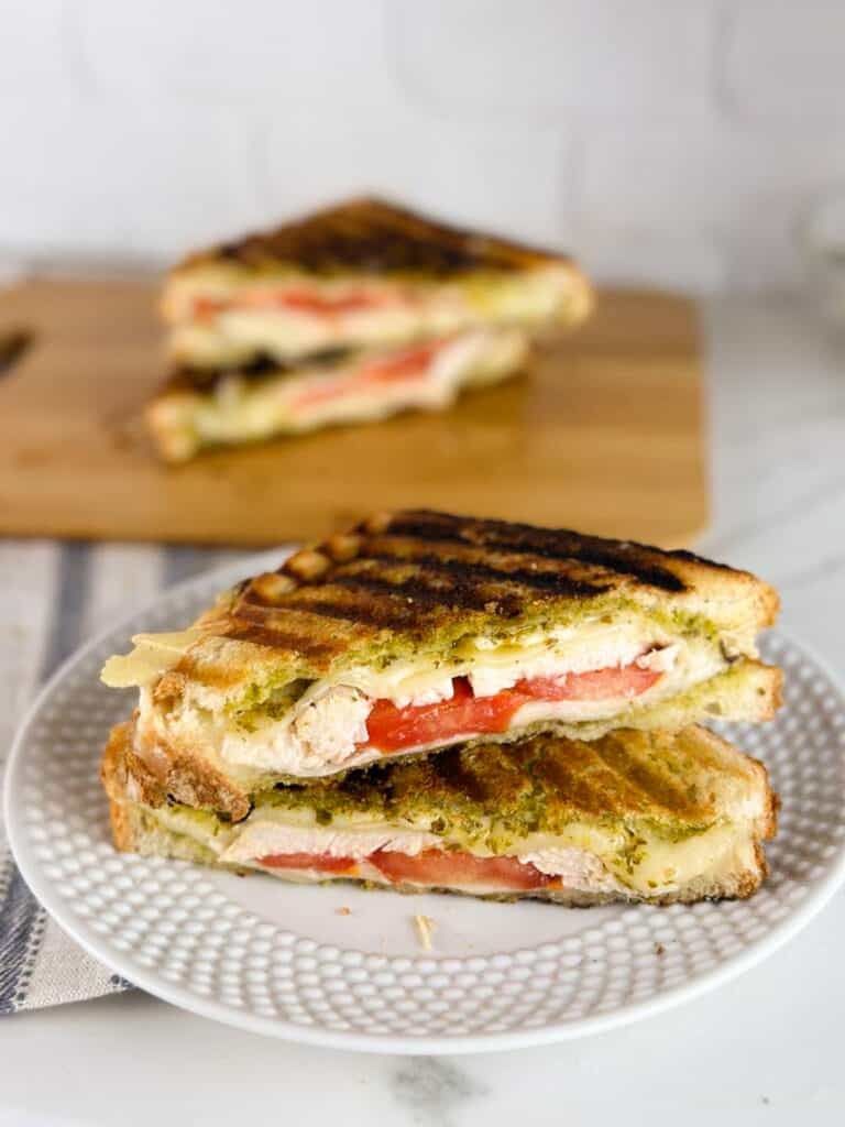 Turkey pesto paninis cut in half on a plate