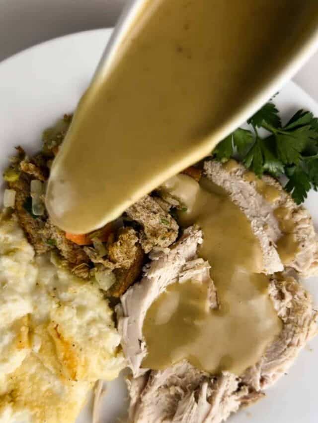 Turkey gravy from drippings poured over a plate of Thanksgiving dinner