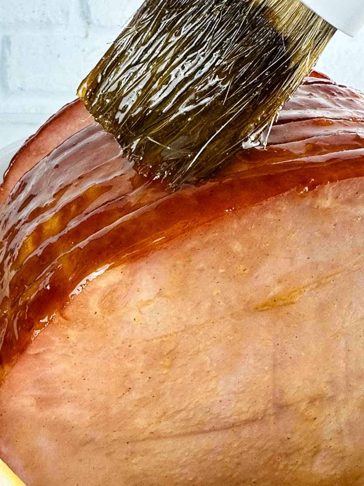 Brown Sugar Ham Glaze (3-ingredient ham glaze) being basted onto a ham