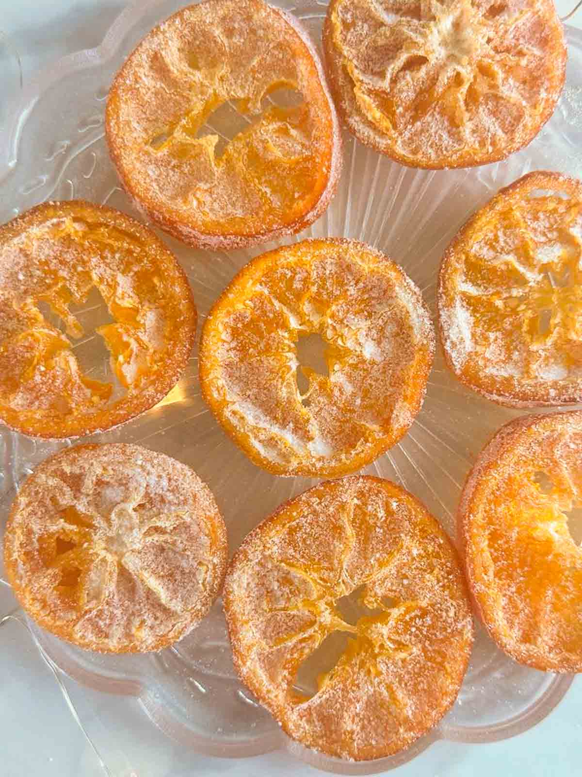 Candied orange slices dipped in granulated sugar on a clear plate.