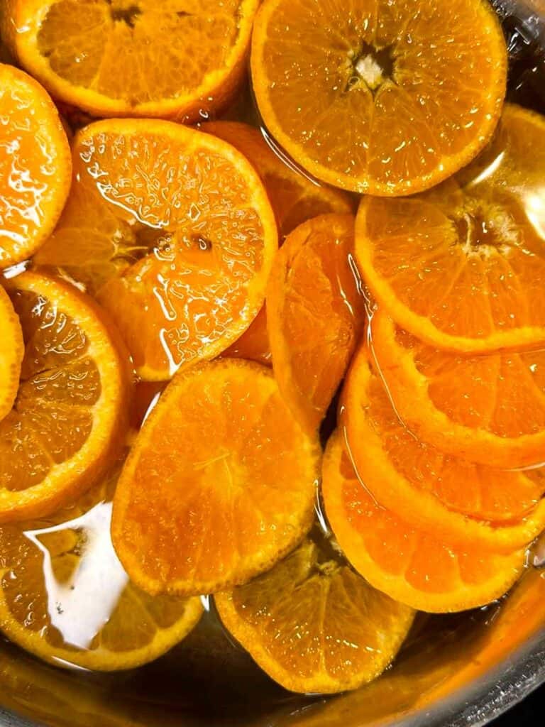 Orange slices in pot of simmering sugar water.