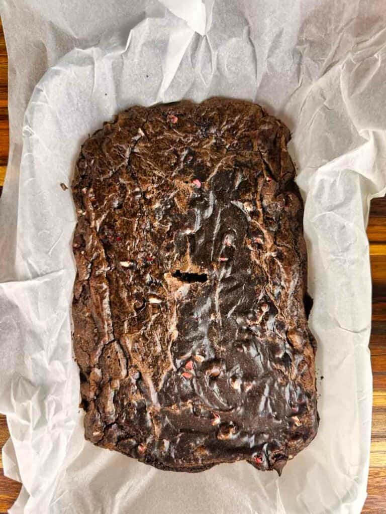 Baked candy cane brownies in a parchment paper lined baking dish.