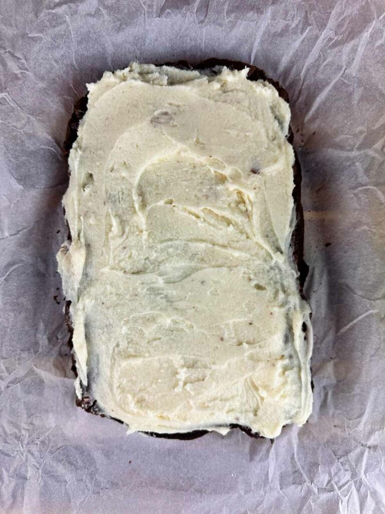 Frosted candy cane brownies on top of a sheet of parchment paper.