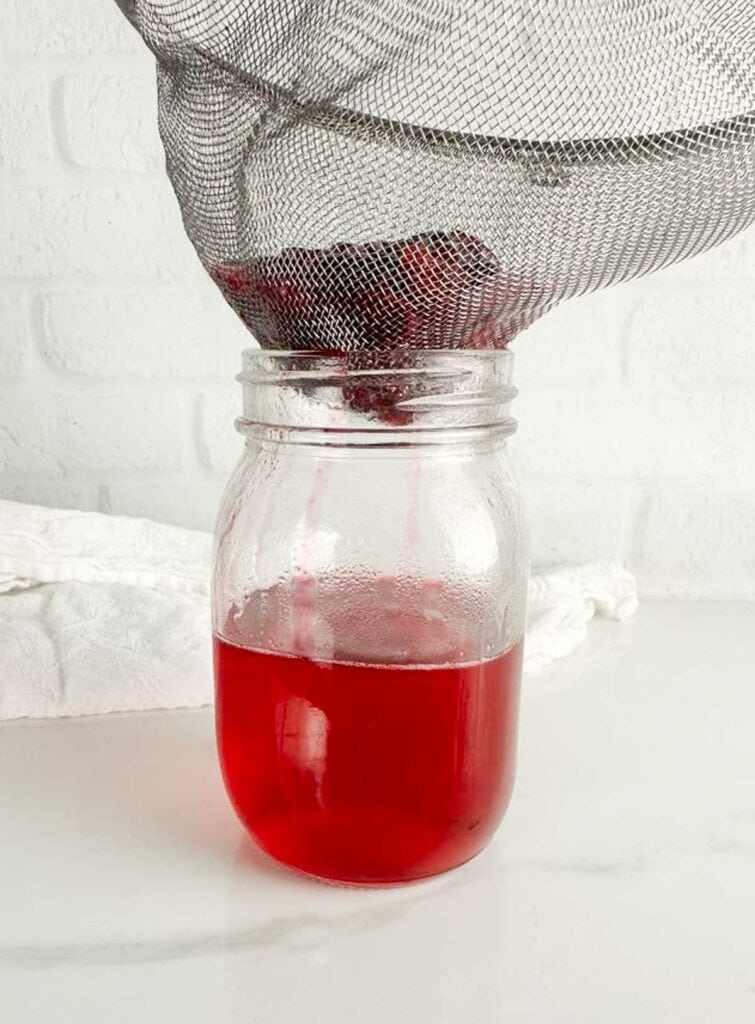 Picture of straining the cranberries out of the simple syrup.