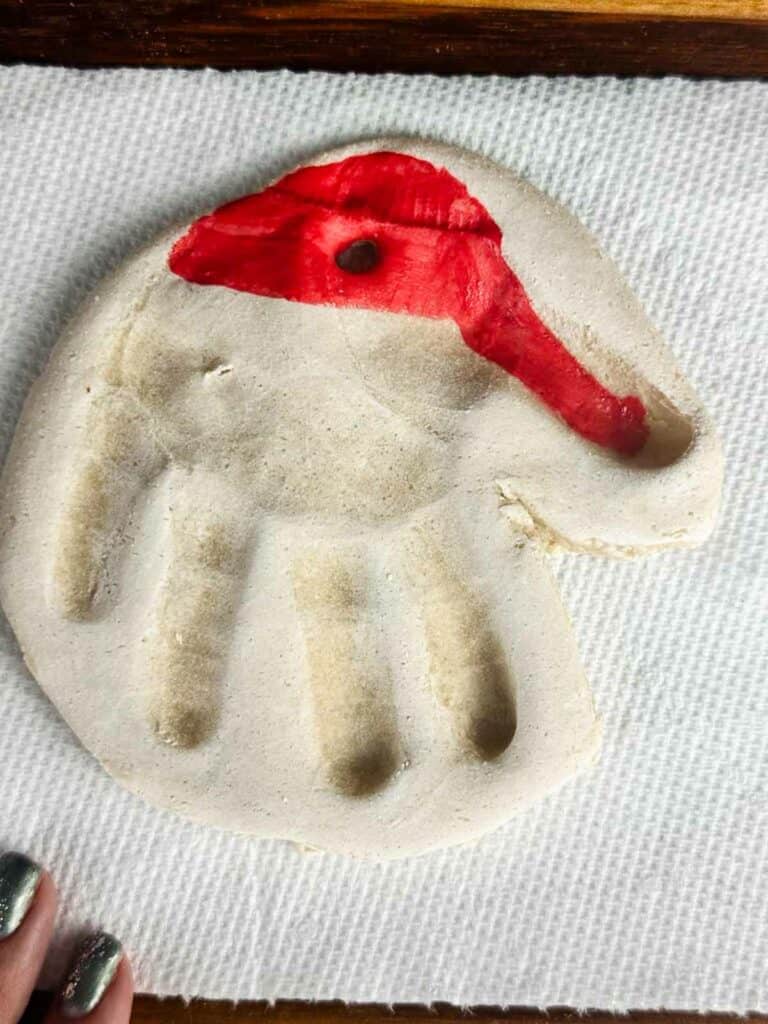 Baked salt dough ornament handprint with a painted on Santa hat.