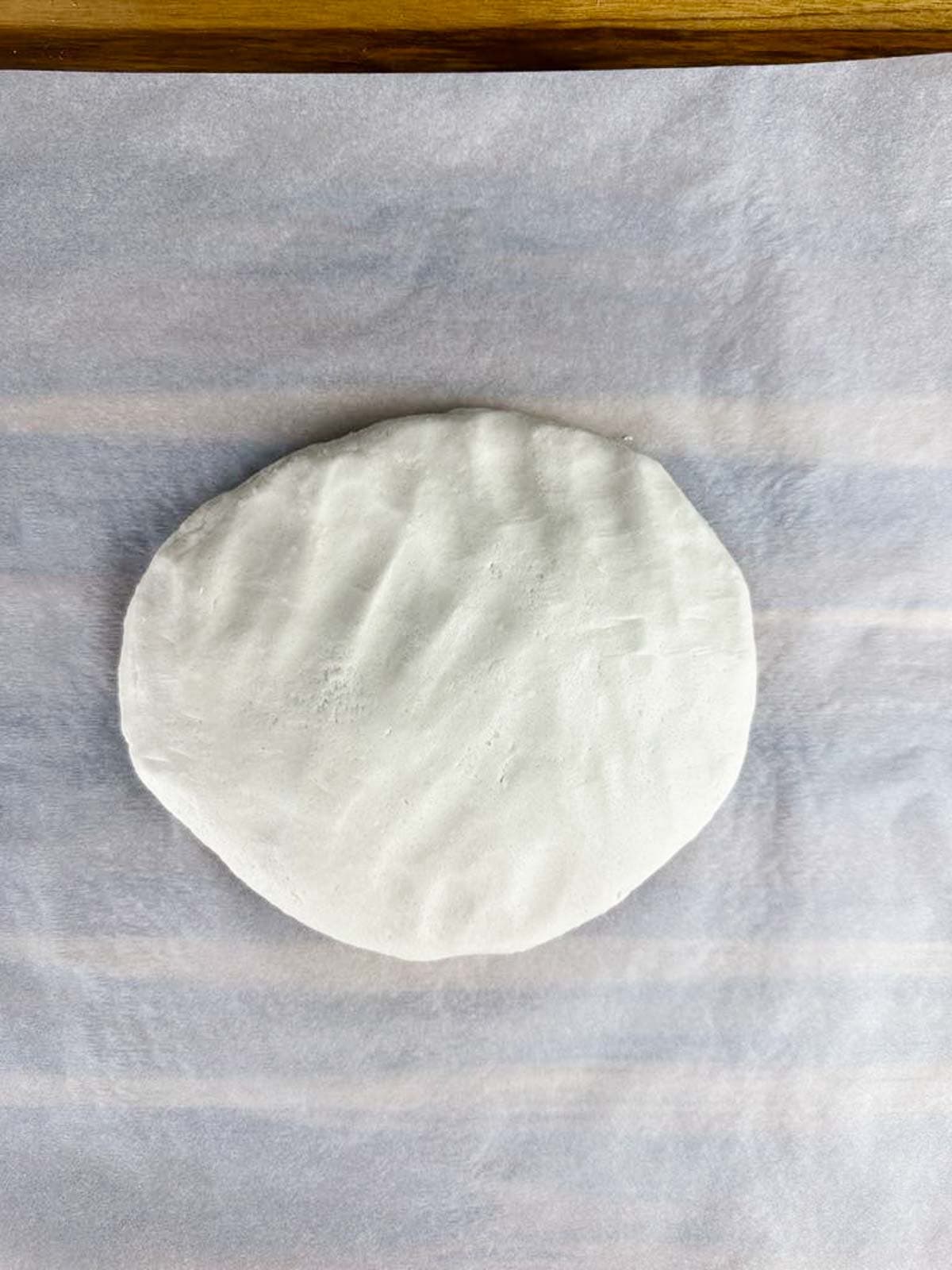 Picture of salt dough for ornaments flattened on a sheet of parchment paper.