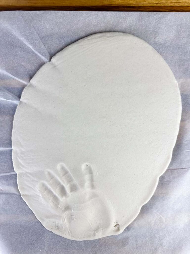 Salt dough fully rolled out with a child's handprint in the lower portion of dough.