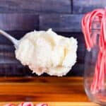 Scoop of peppermint frosting with candy canes in the background. Set in front of butcher block counter and wood back splash.