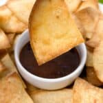 Dipping a homemade corn tortilla chip in a red dipping sauce.