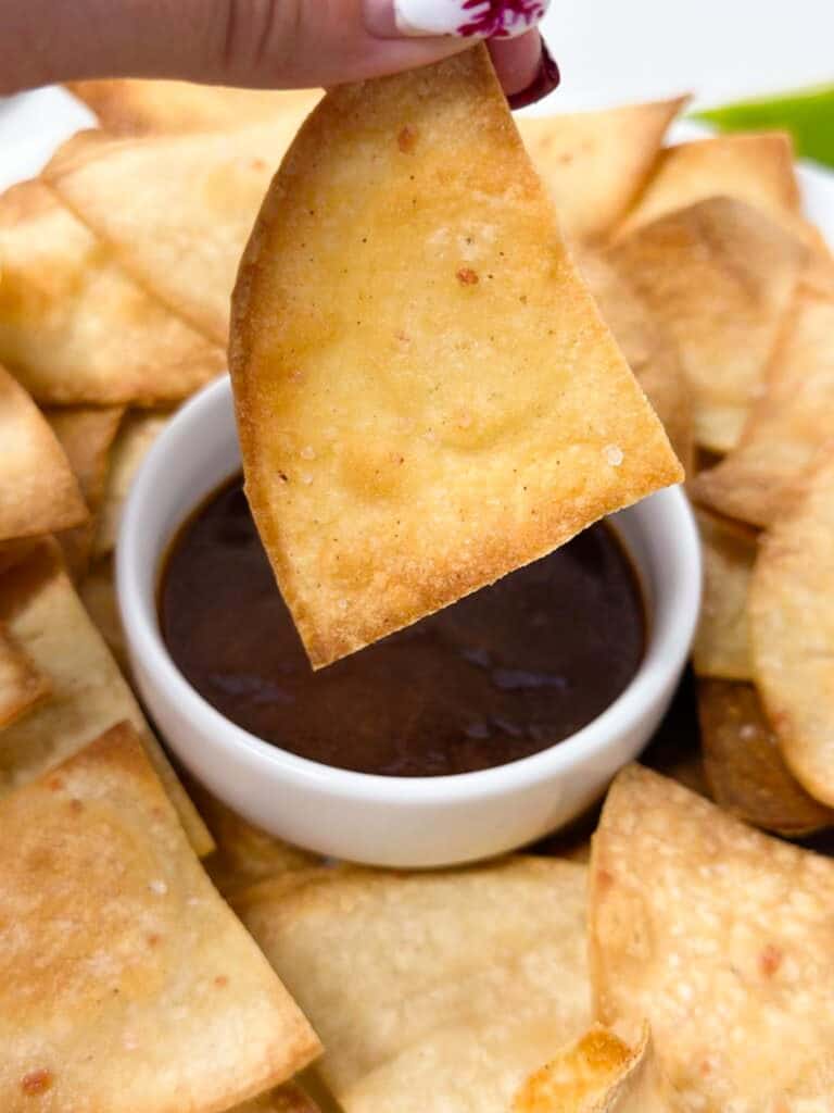 Dipping a homemade corn tortilla chip in a red dipping sauce.