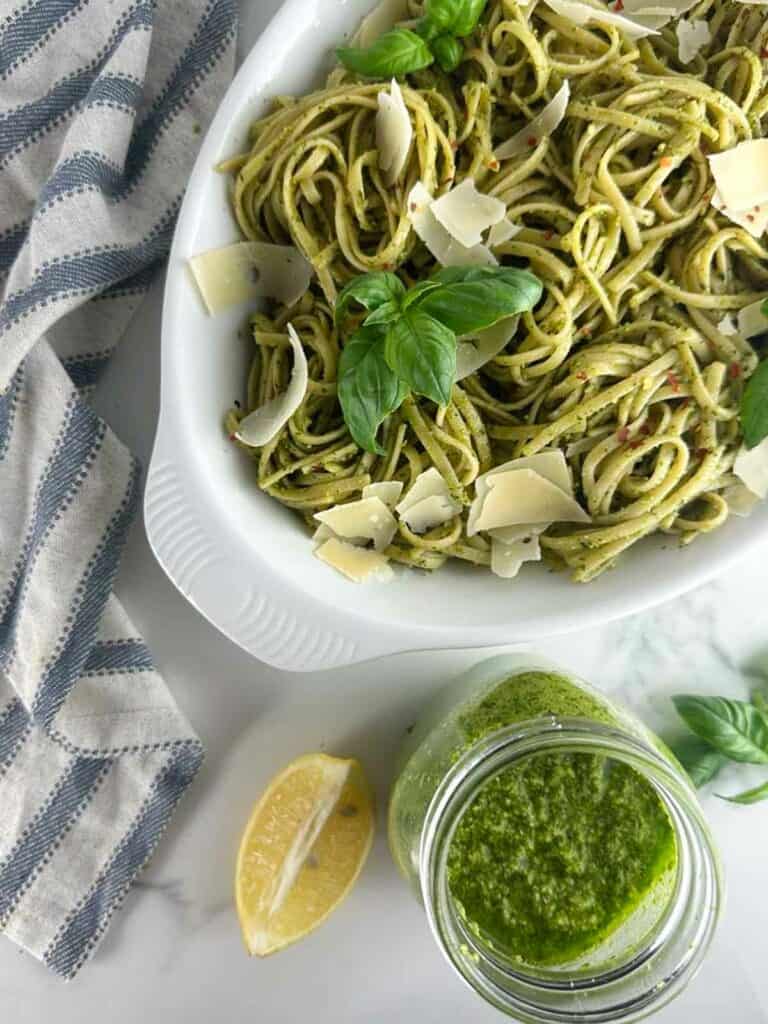 Pasta al pesto in a dish with a jar of homemade pesto