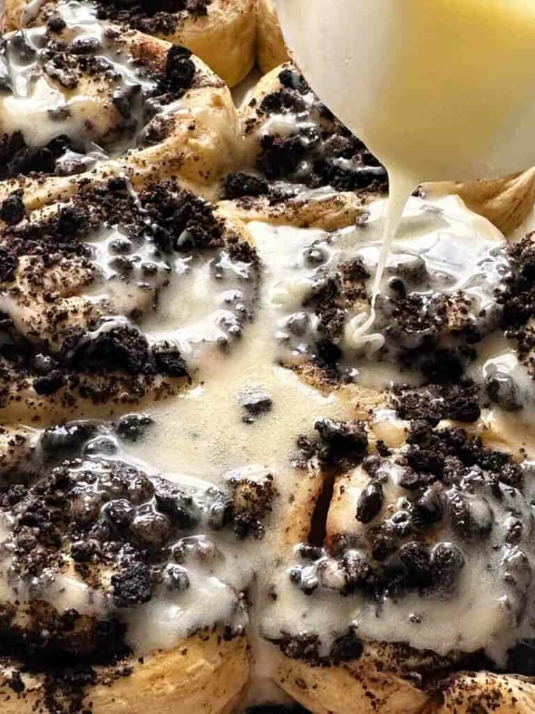 Pouring icing on top of Oreo cinnamon buns.