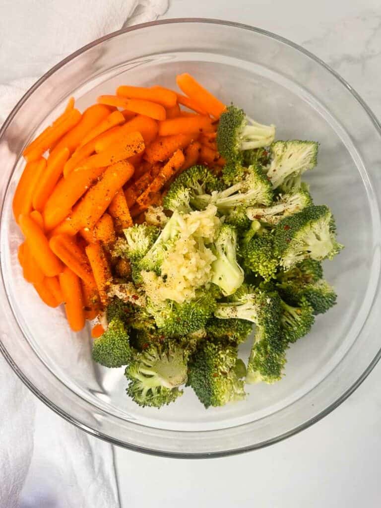 All ingredients for roasted broccolis and carrots in a mixing bowl.