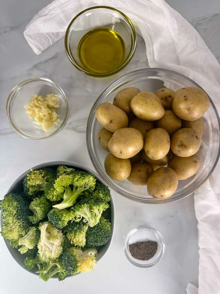 Ingredients for roasted potatoes with broccoli: broccoli, potatoes, olive oil, salt, pepper, and garlic.