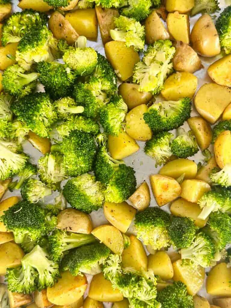 Adding broccoli to potatoes to finish roasting.