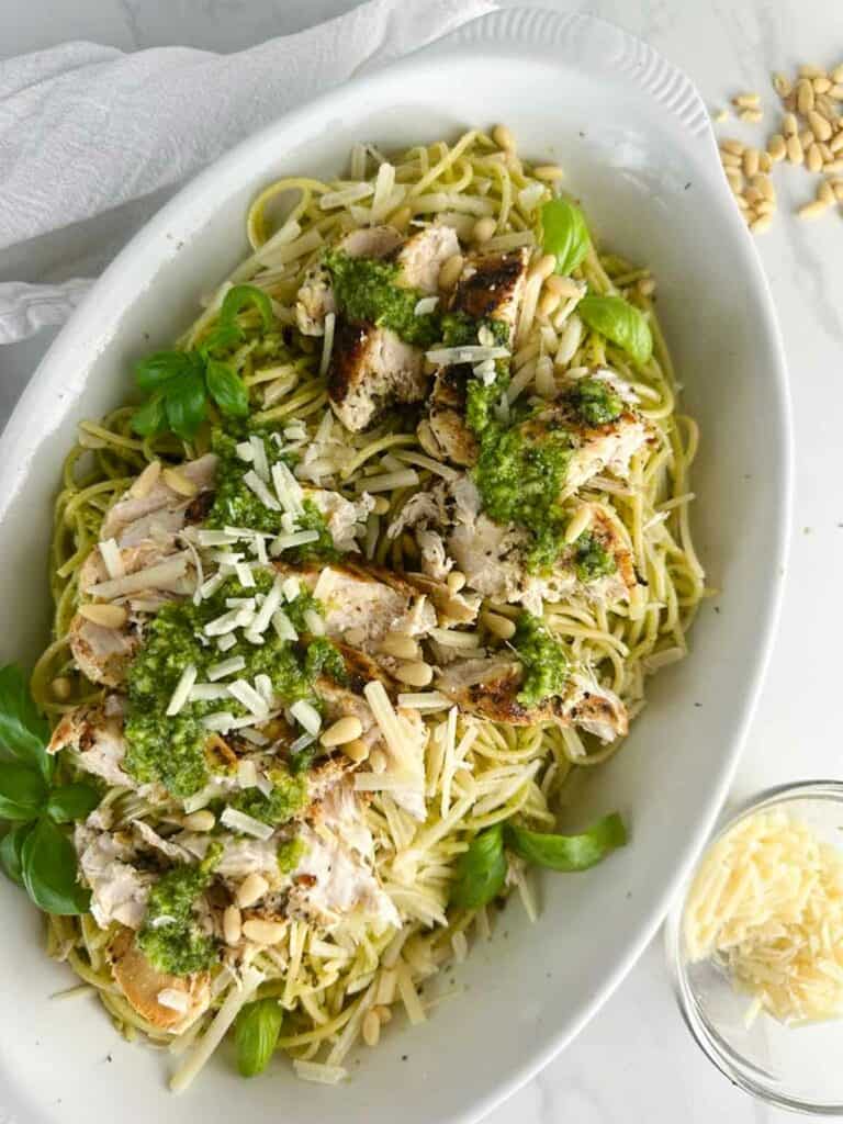 A serving platter full of chicken spaghetti pesto