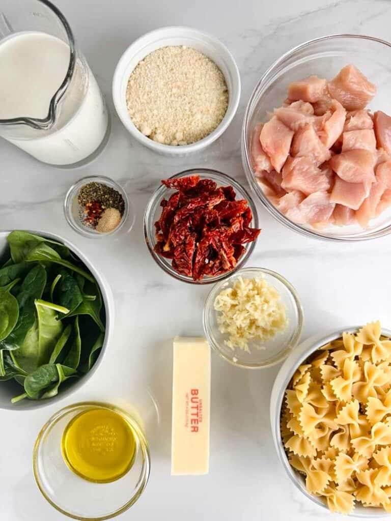 Ingredients for Marry Me Chicken Pasta: Chicken, Bow Tie Pasta, Butter, Olive Oil, Garlic, Sun Dried Tomatoes, Spinach, Spices, Heavy Cream, and Parmesan Cheese