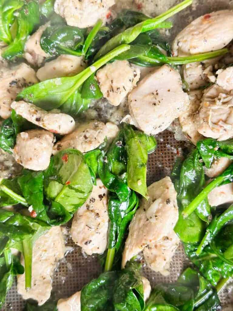 Spinach slightly wilted in a saute pan with chicken for Marry Me chicken pasta