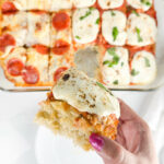 Hand holding a square of focaccia bread pizza