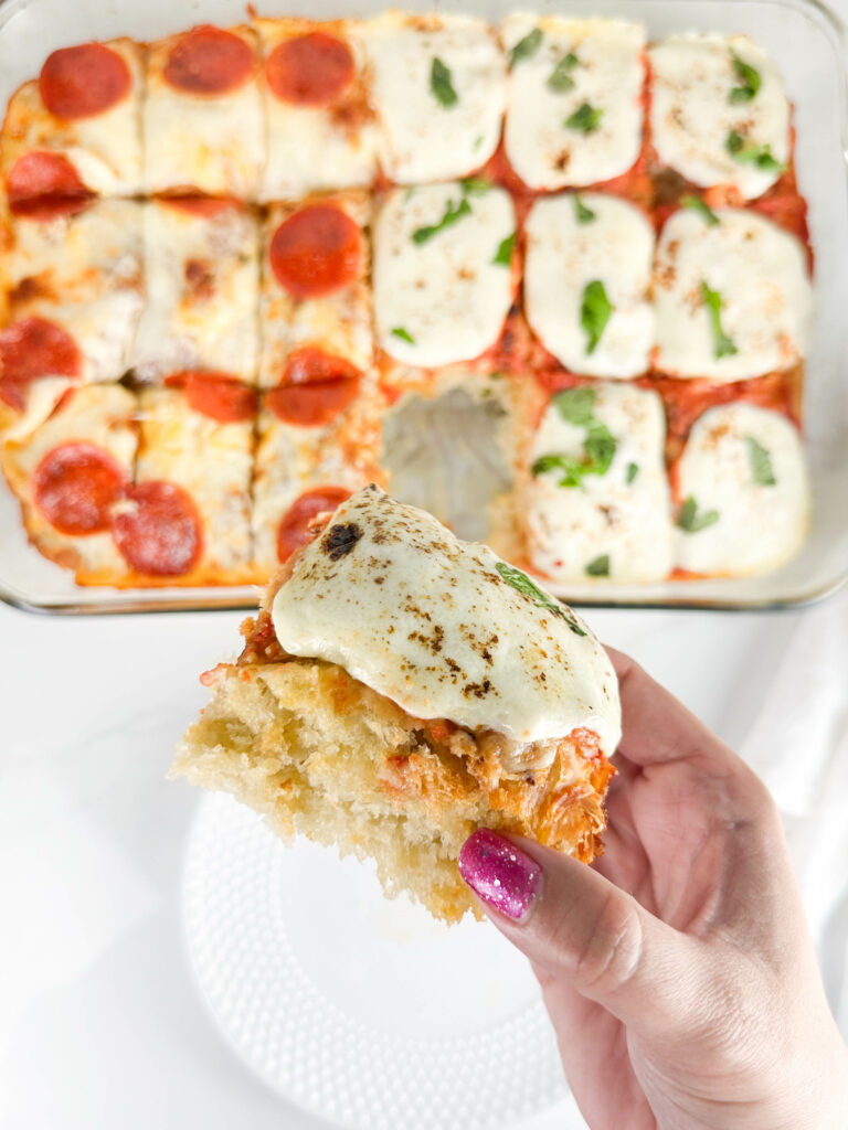 Hand holding a square of focaccia bread pizza