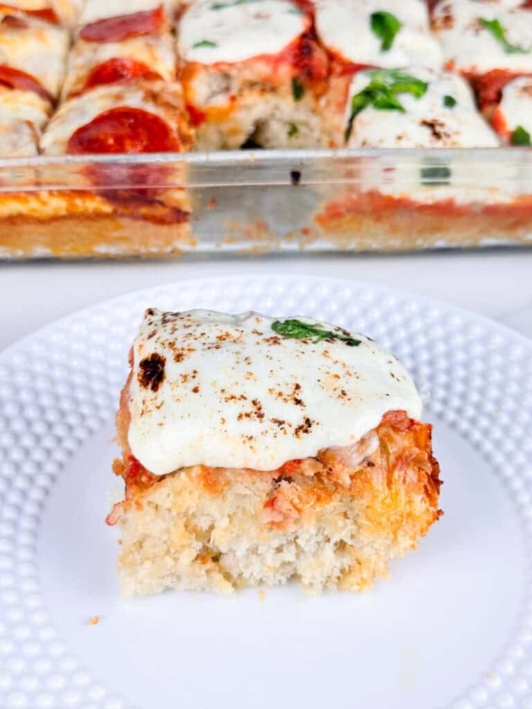 Serving of focaccia bread pizza with the rest of the pizza in background