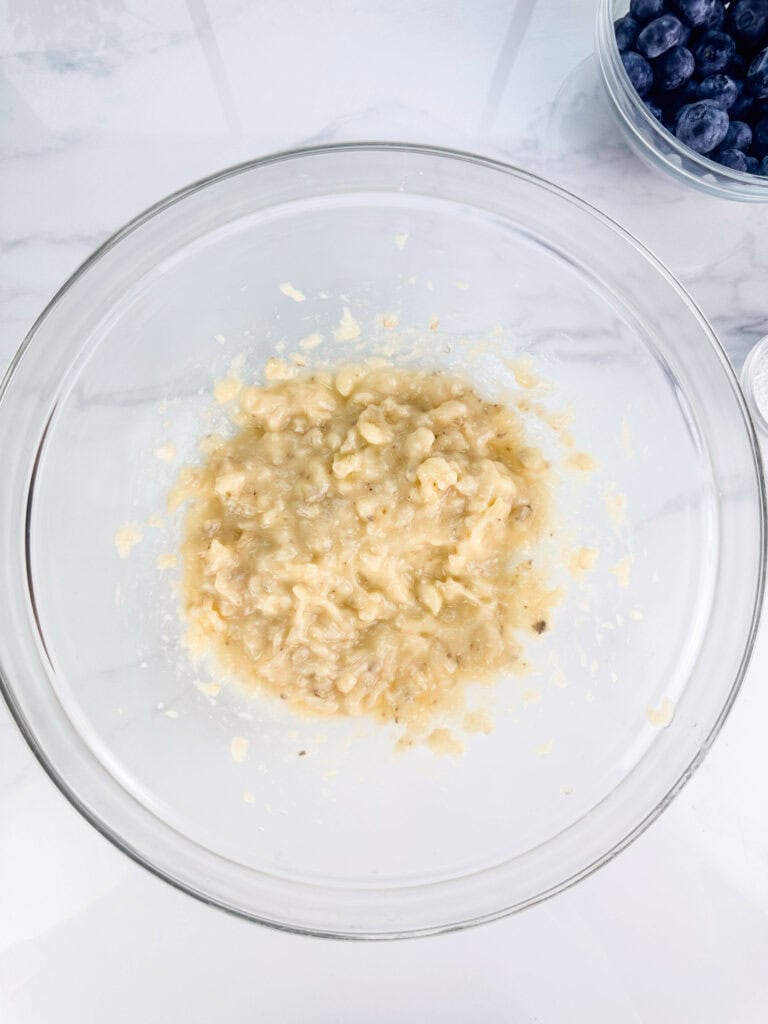 Mashed bananas in a mixing bowl ready to be turned into blueberry banana nut bread