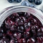 Blueberry compote in a jar with blueberries. Text reads, blueberry compote, seasonedsprinkles.com