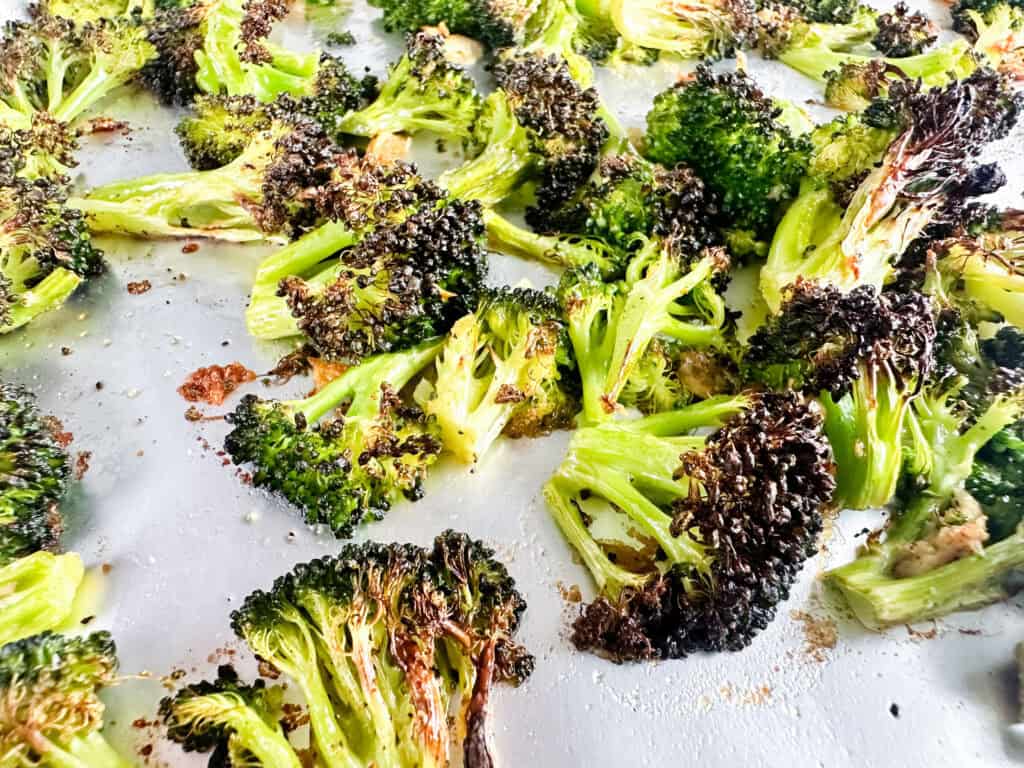 Garlic and roasted broccoli on a cookie sheet.