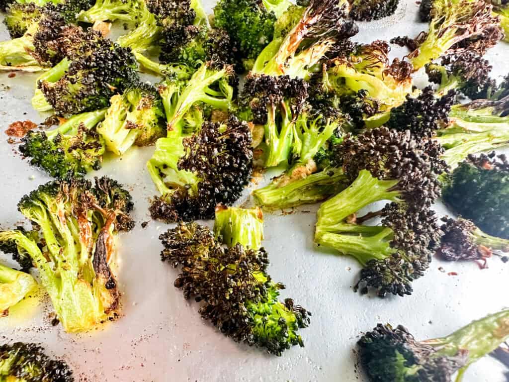 Garlic and roasted broccoli on a cookie sheet.